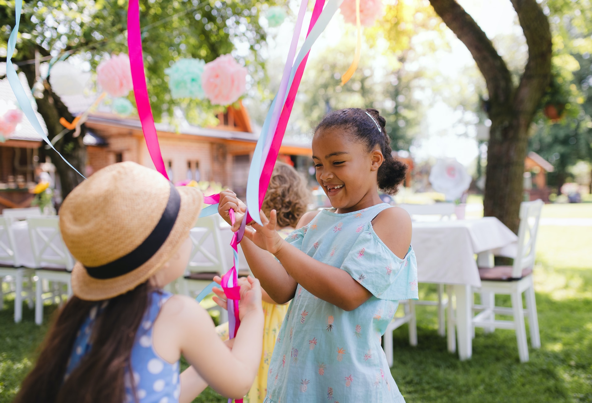 Happy children playing with coloured streamers outside.