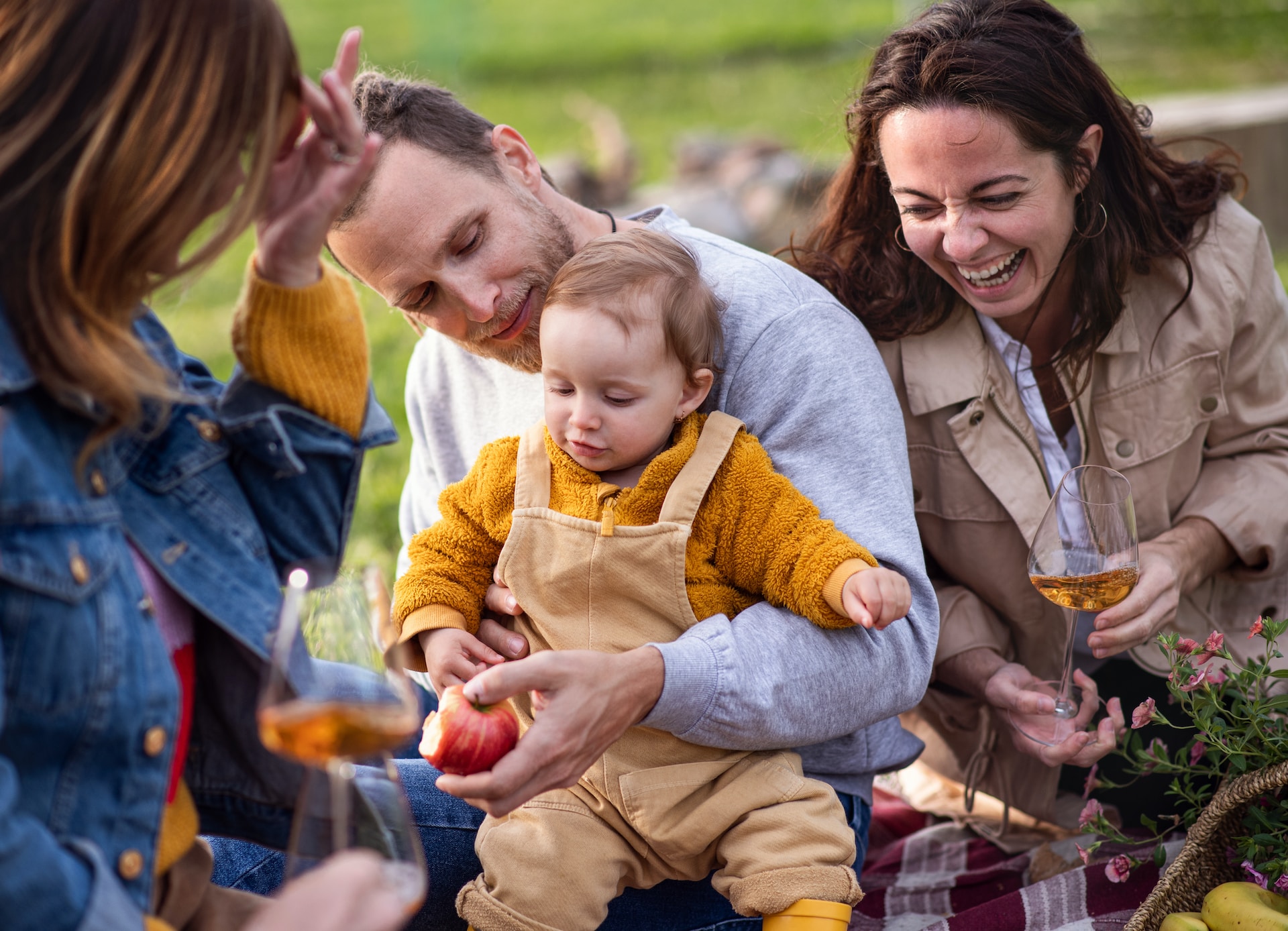 Parents laughing whilst holding baby outdoors.